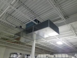 Rooftop-mounted supply fans may introduce objectionable sound levels into staffed low-noise production areas. These are addressed with an in-line duct silencer integrated with a distribution plenum that reduces air velocity noise.